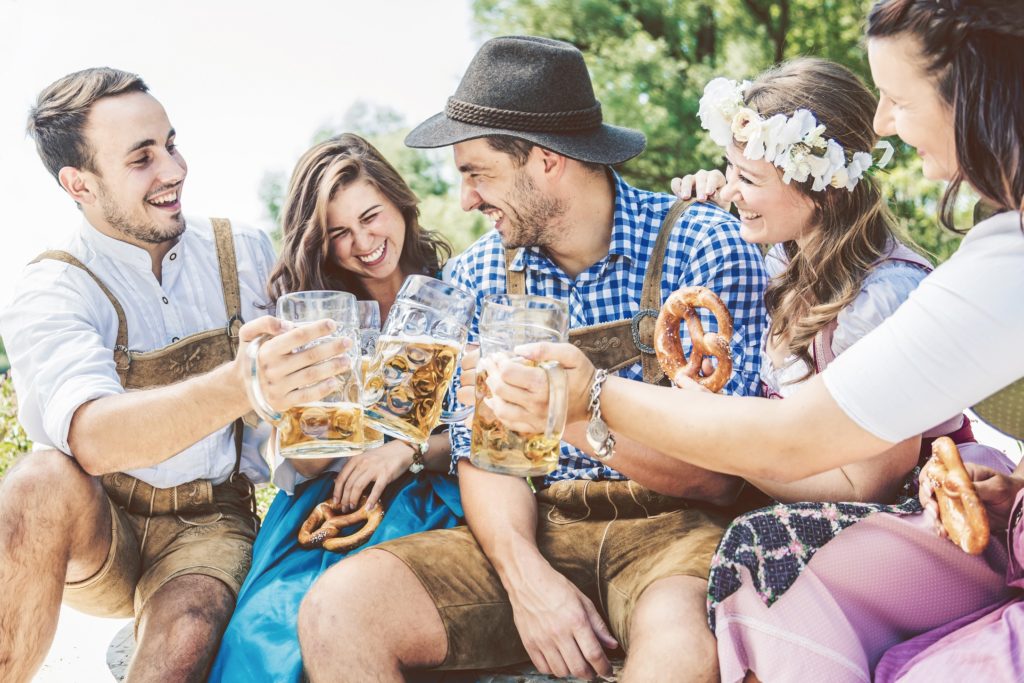 Five friends eating pretzels and drinking beer, dressed up for Oktoberfest