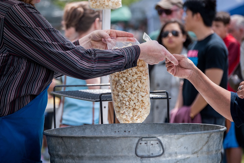 Woman buying popcorn from man at a festival