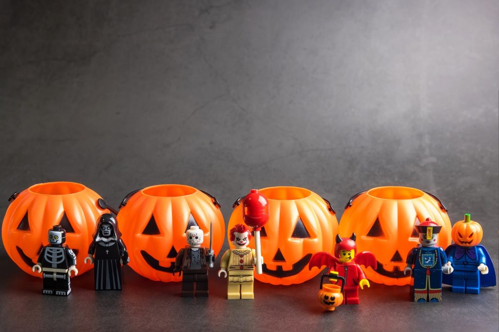 Various Lego characters dressed in Halloween gear with pumpkin buckets.